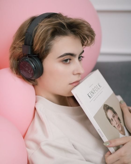 Chica escuchando música y con un libro en sus manos.