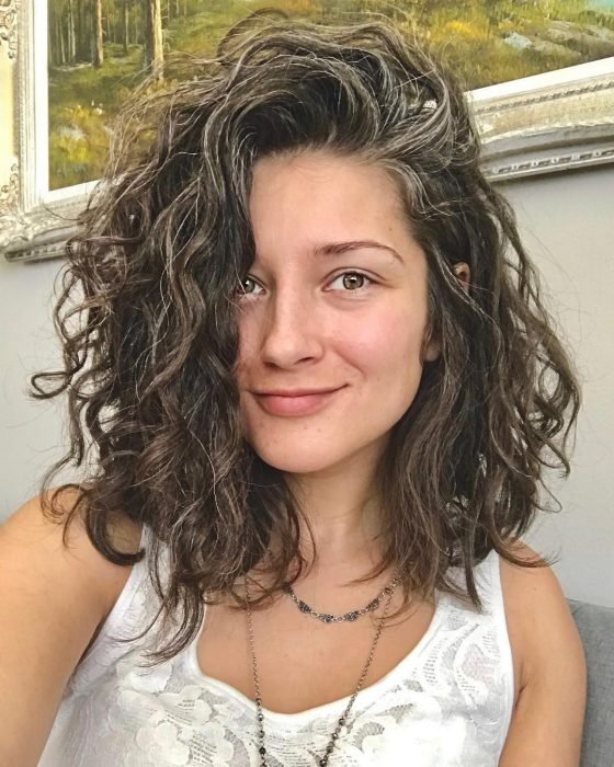 Mujer joven con pelo corto y rizado con canas