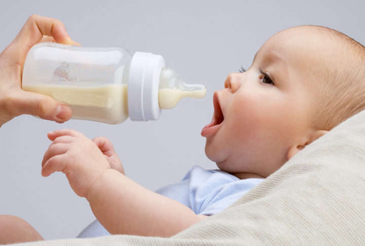 Un bebé abre la boca cuando le traen un biberón de leche.
