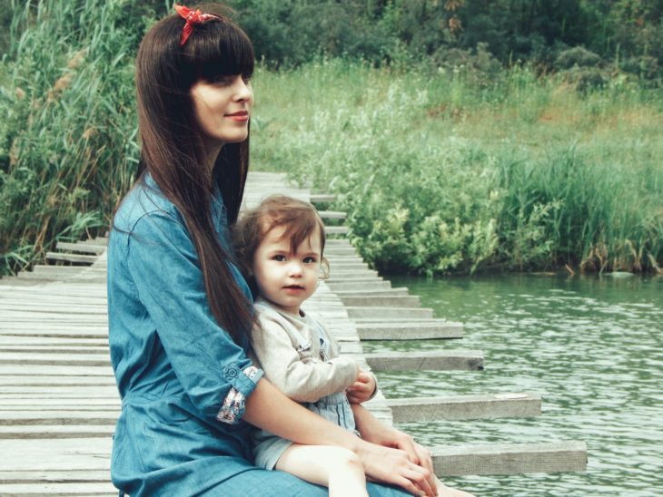 Las tías son como segundas madres para los sobrinos;  niña con pañuelo en la cabeza y pelo largo y liso con flecos;  llevar un bebe a la orilla de un rio