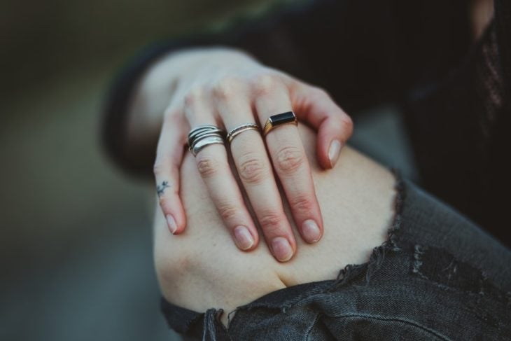 Manos de mujer con anillos en la rodilla.