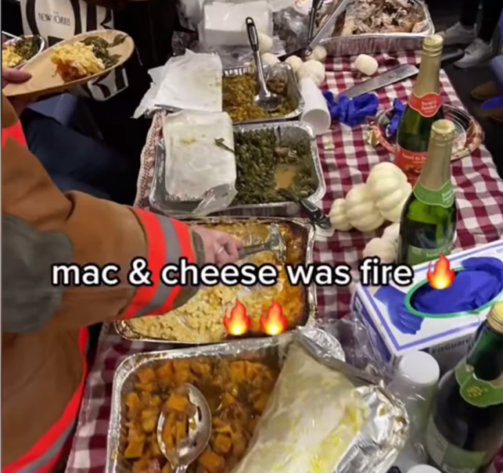 mesa con mantel a cuadros blancos y rojos, sobre la que se encuentran varias bandejas de aluminio con diversos alimentos que se preparan para el día de acción de gracias.  alrededor de la mesa están las personas que sirven la deliciosa comida 