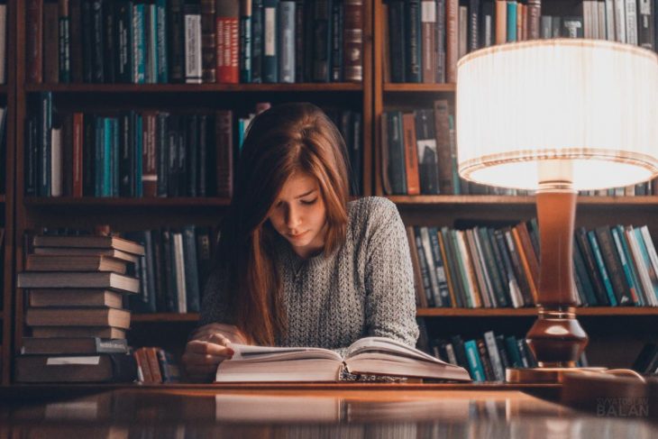 Joven leyendo un libro en la biblioteca