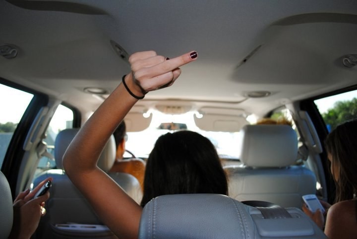 Chica parando el dedo de en medio en un auto 