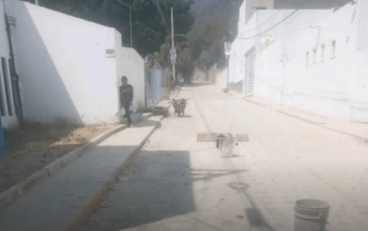 una imagen algo borrosa de una calle de alguna ciudad latinoamericana se ve la figura de una persona recargada en la pared de una de las viviendas