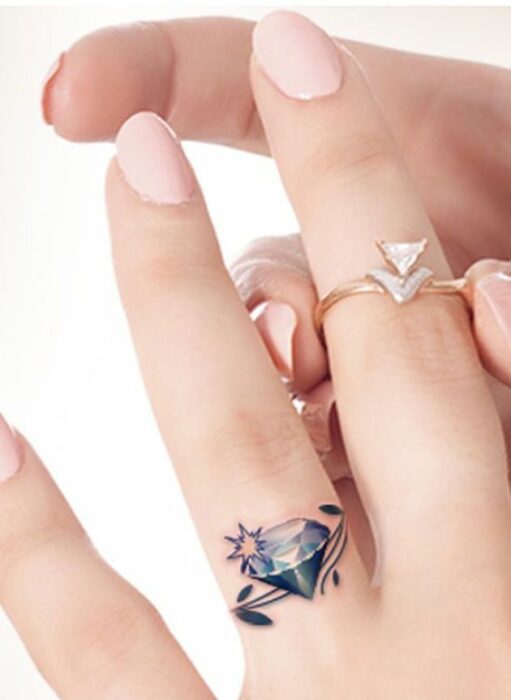 imagen de los dedos de una chica mostrando un tatuaje con un diamante en el dedo anular