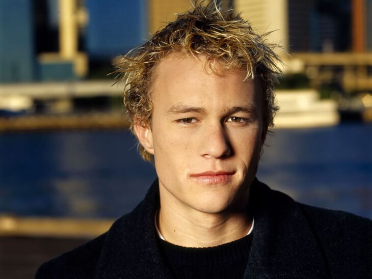 Heath Ledger posa con ropa oscura en un ambiente con agua de fondo