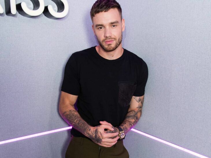 Liam Payne registrado en la esquina de una habitación, lleva ropa oscura y muestra tatuajes en los brazos