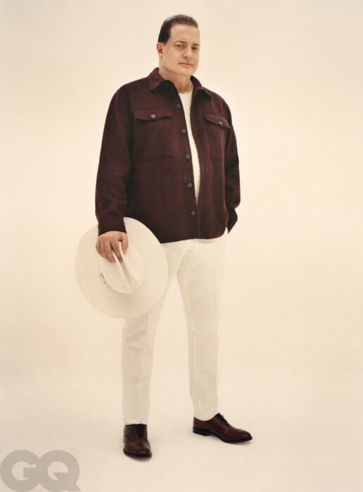 Brendan Fraser vistiendo una gabardina café con pantalón blanco para la revista GQ