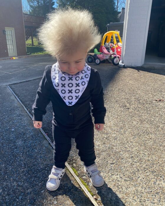 Niño mostrando su cabello rubio alborotado en el patio de una casa