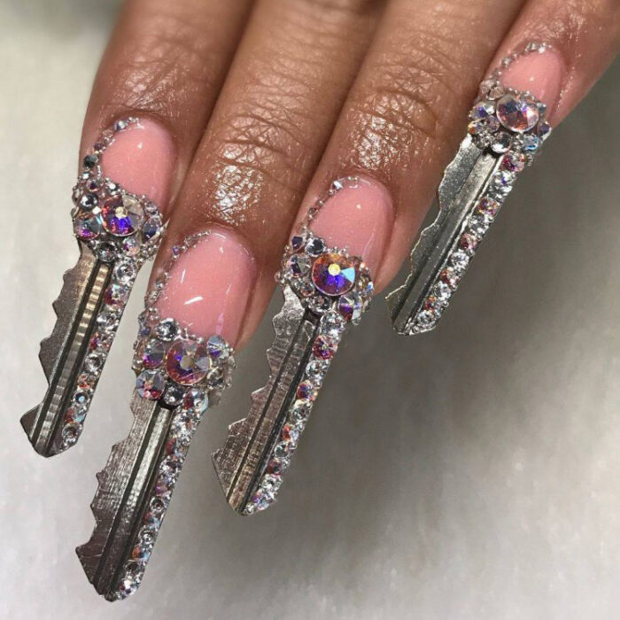 manos de una chica con uñas en forma de llaves con diamantes