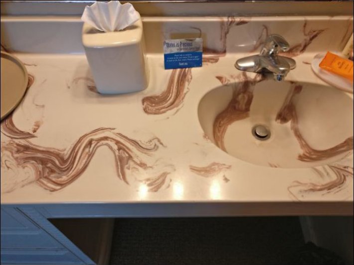 lavabo de un baño de mármol color beige que parece color popo