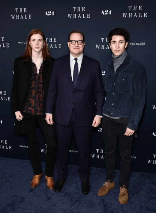 Brendan Fraser con sus hijos en la premier de la película The Whale. Fraser mantuvo un estilo clásico con un traje azul marino a rayas, mientras que Holden lució una chaqueta de gamuza azul marino sobre un cuello alto gris, y Leland optó por una camisa abotonada estampada que realzaba su cabello naranja.