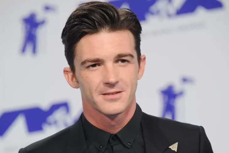 Drake Bell posa para las cámaras en un evento público, luciendo sereno y con ropa formal oscura