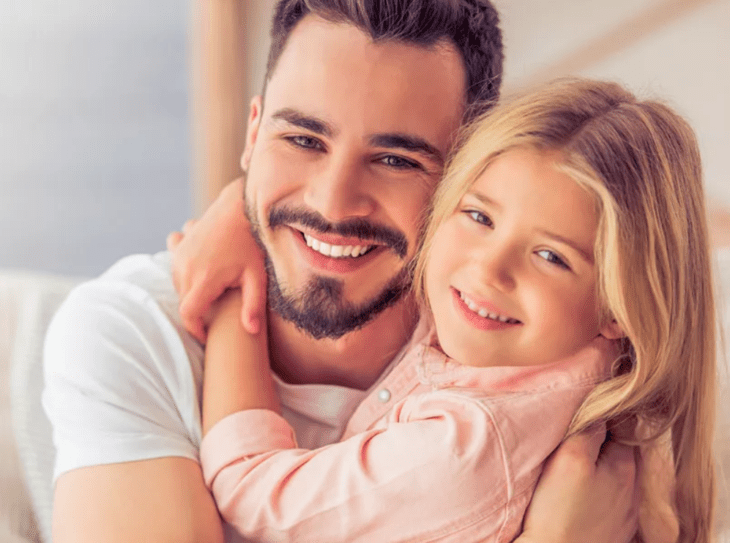 una pequeña abraza con cariño a su padre, ambos sonríen