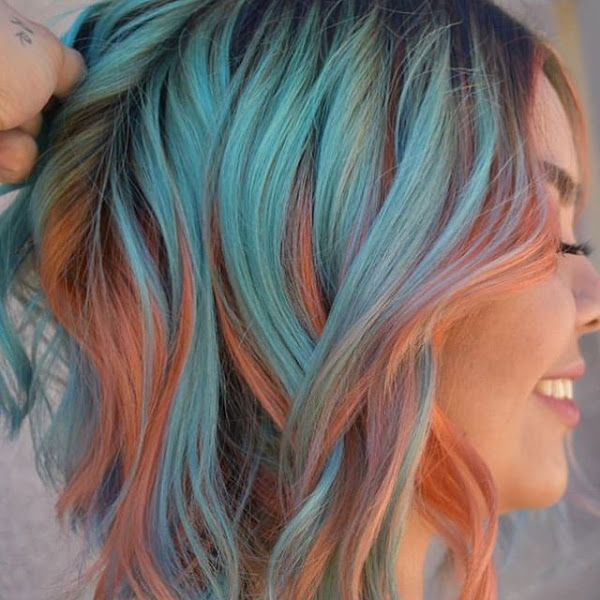 chica modelando un cabello corto en con mechas en color azul y naranja 