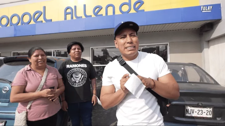 tres personas en el exterior de la tienda departamental Coppel, uno de ellos vestido con camiseta blanca y gorra, junto a un hombre y una mujer en atuendos informales