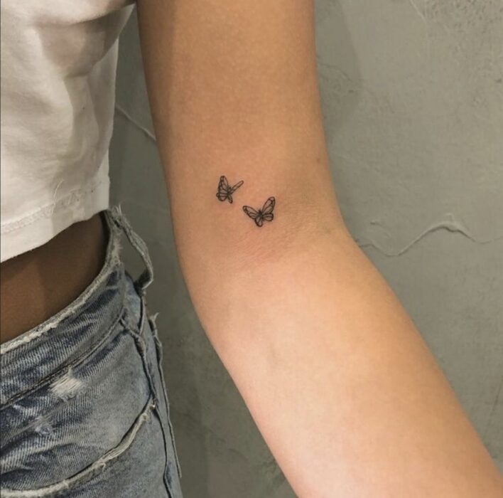 Chica con un tatuaje en la mano en forma de mariposa 
