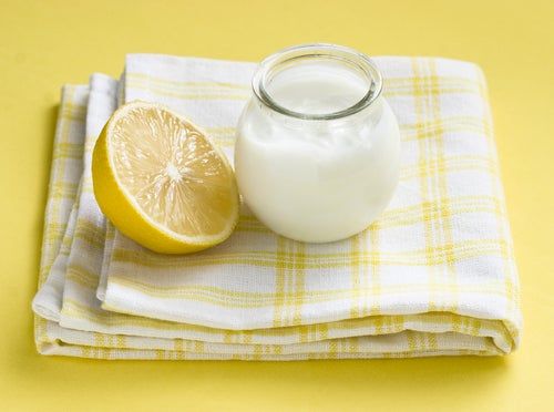 Frasco lleno de yogur natural junto a una lima grande