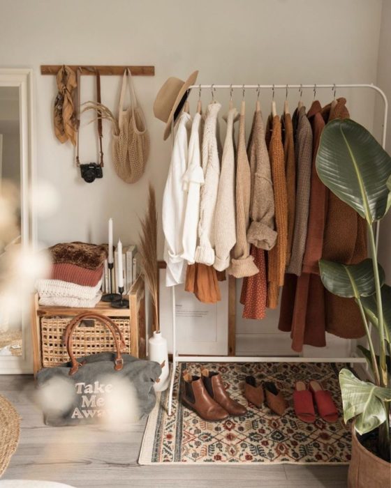 Perchero con prendas colgadas, algunos bolsos y zapatos