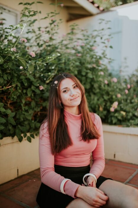 Chica con cuéter rosa sentada en un jardín