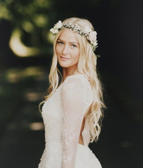 Peinado de novia con cabello ondulado natural con una corona de flores