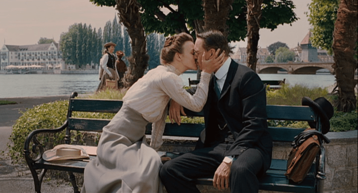 Escena de la película Un método peligroso, pareja de los años 30 sentada en una banca del parque besándose