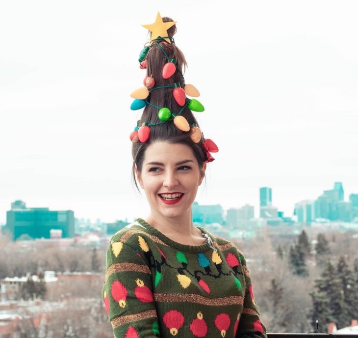 Chica llevando suéter navideño posando para una foto sobre una montaña