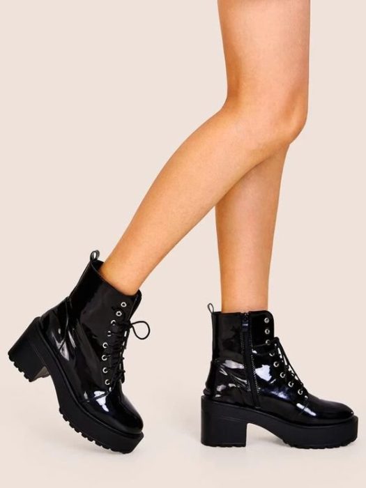 Chica llevando botas antas de charol en tono negro