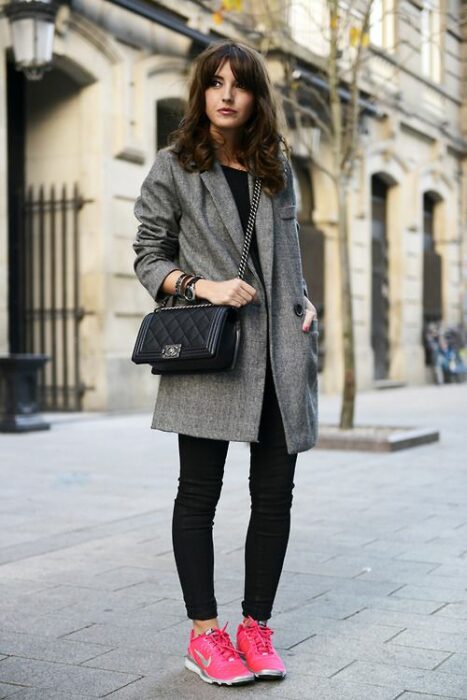 Chica llevando jeans negros con saco gris y tenis en color rosa fucsia; 13 Outfits con tenis neón para deslumbrar a cada paso