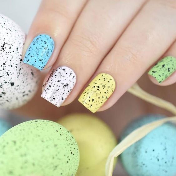 Manicura en colores pastel con diseño inspirado en huevos de dinosaurio