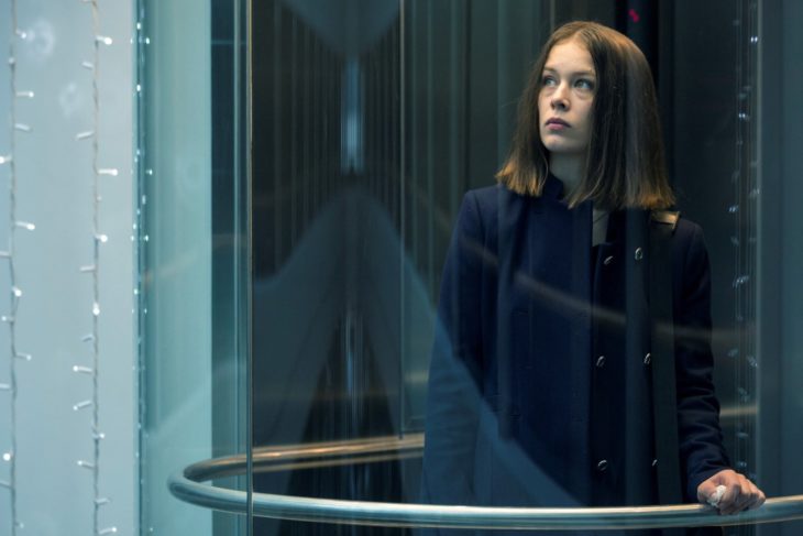 Escena de la serie alemana Bad Banks, una mujer mirando a través de un vidrio por un pasillo largo