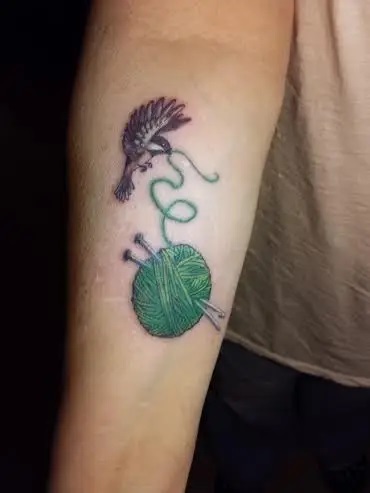 Abuelita mostrando su tatuaje en forma de colibrí con una bola de estambre