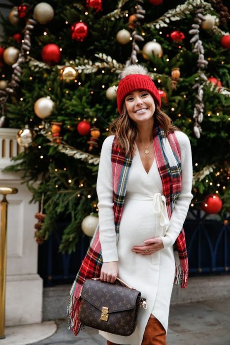 Chica usando un outfit de invierno para presumir con su embarazo