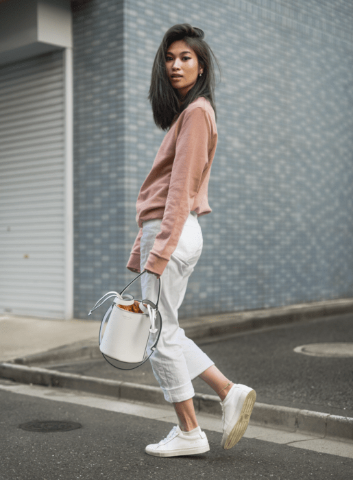 Chica usando jeans capri blancos, sudadera rosa, y bucket bag blanca
