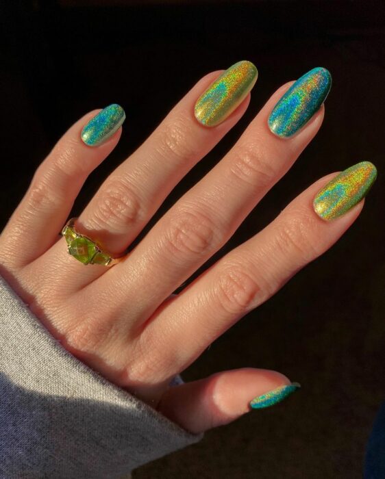 Chica con uñas holográficas en tonos verdes