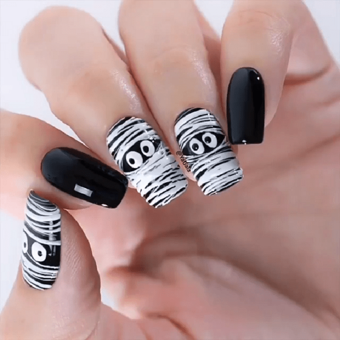 Manicura en color negro con diseños de momias en varios dedos
