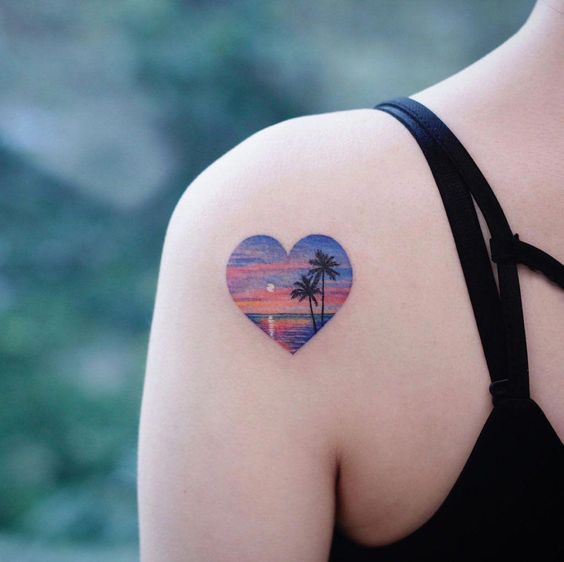 Chica con tatuaje en forma de corazón que representa el mar en un atardecer