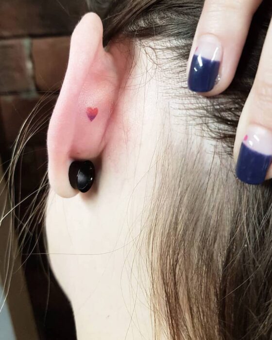 Chica con un tatuaje en la oreja en forma de corazón rojo