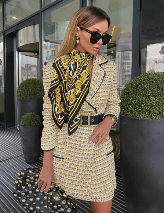 Victoria Fox usando blazer amarillo con detalles negros, cinturón negro y pañuelo de tonalidades similares