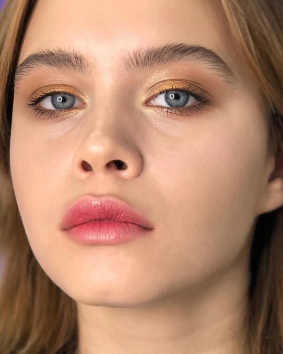 Chica de ojos azules con tinta de labios en un suave tono rojo