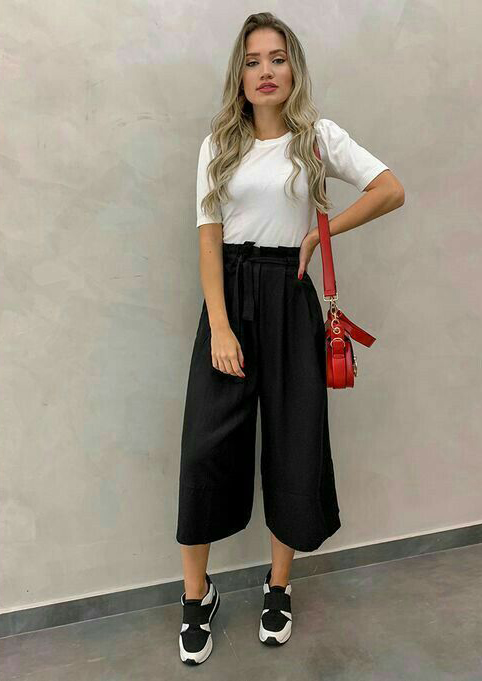 Chica con un pantalón estilo palazzo, blusa blanca y tenis