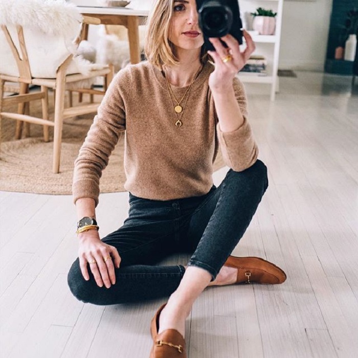 Chica usando jeans negros, mocasines y suéter cafés