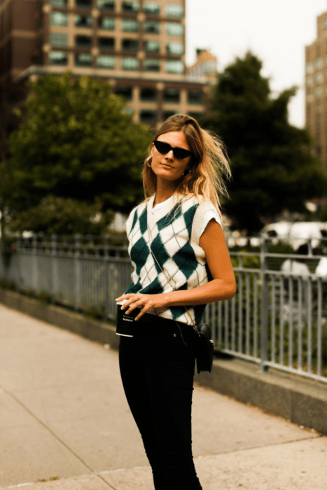 Chica usando chaleco de rombos y pantalones negros
