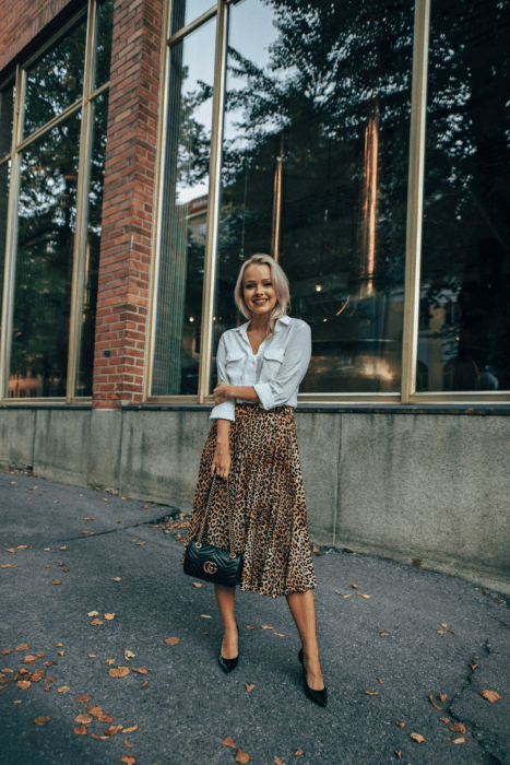 Chica usando una falda midi con estampado animal print con una blusa de seda blanca