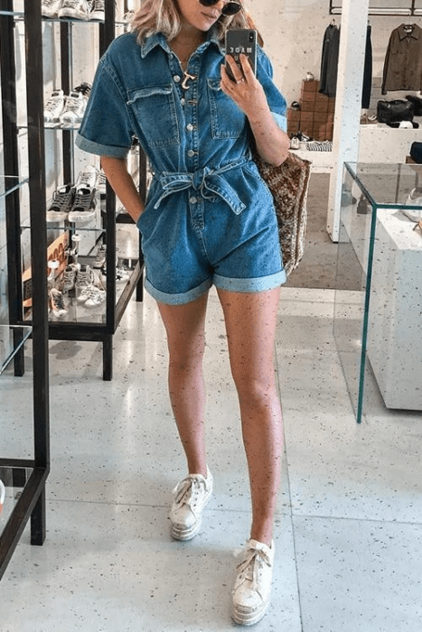 Chica usando un jumpsuit de color mezclilla con tenis blancos