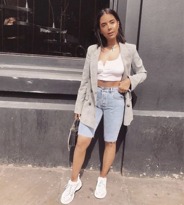 Chica con bermudas de mezclilla, top blanco y tenis blancos