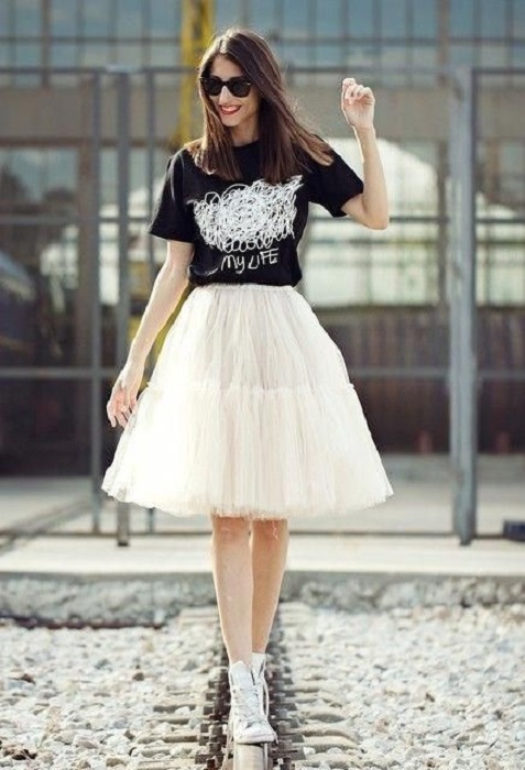 Chica usando falda de tul color perla con blusa negra y tenis blancos