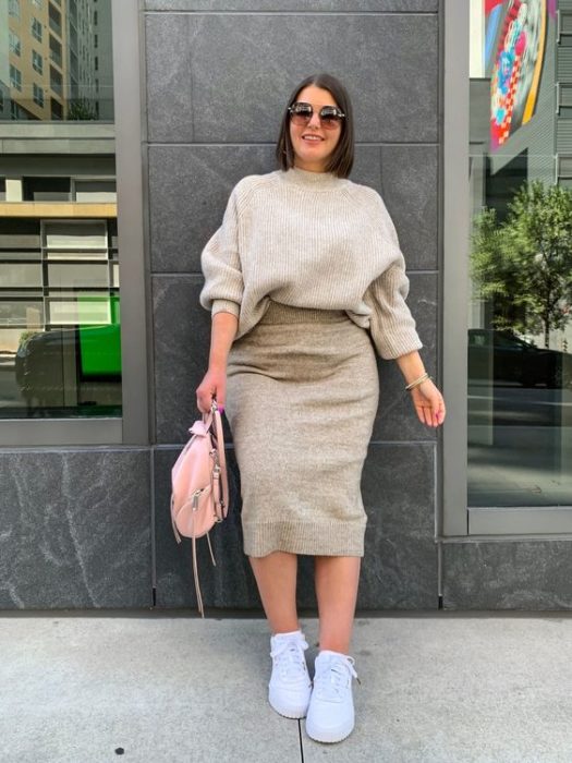 Chica curvy usando tenis blancos, falda lápiz y suéter color arena