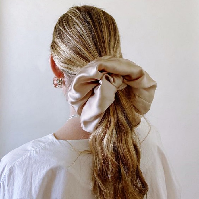 chica de cabello largo rubio usando una coleta con scrunchie de seda